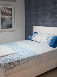 a bed with blue and white pillows and a window at Apartments Leo in Bar