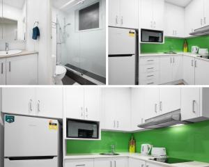 a kitchen with white cabinets and a green wall at 611 Lovely Central Super Cosy Studio Heart CBD in Melbourne