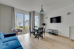 a living room with a blue couch and a table and chairs at Orłowska Riwiera - Blue Mandarin Apartments in Gdynia