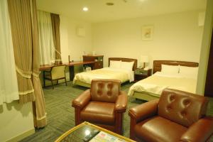 a hotel room with two beds and a desk at Hotel Soleil in Iwaki