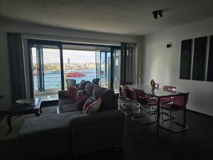 a living room with a couch and a table with chairs at Sea View over Valletta Harbour 3 bedrooms 2 S4 in Sliema