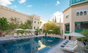 - une piscine avec des chaises et des parasols à côté d'un bâtiment dans l'établissement Palais Faraj Suites & Spa, à Fès