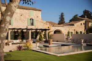 a large stone house with a courtyard with a swimming pool at Maison Roucas - Restaurant et chambres d'hôtes in Solérieux