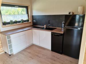 a kitchen with a black refrigerator and white cabinets at Hortensja in Rusinowo