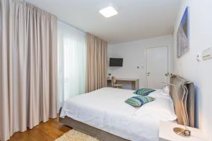 a bedroom with a white bed and a window at Dubrovnik Luxury Residence – L’Orangerie in Dubrovnik