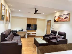 a living room with leather furniture and a flat screen tv at HOTEL TOUCHWOOD in Visakhapatnam
