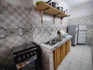 a kitchen with a sink and a stove and refrigerator at TDD a2 in Douala