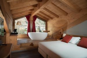 een slaapkamer met een bad en een groot raam bij Miramonti Park Hotel in Bormio