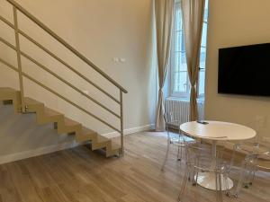 a living room with a staircase and a table and a tv at Les Suites di Parma - Cavour in Parma