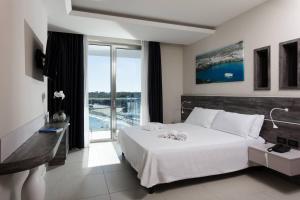 a bedroom with a white bed and a large window at Hotel Belvedere in Torre dell'Orso +37 photos