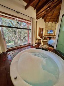 a large bath tub in a room with a large window at Chalés Montanha Serrana - Monte Verde in Monte Verde