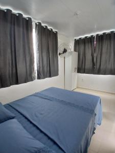 une chambre avec un lit bleu et un ventilateur dans l'établissement Hospedagem dos Massa- Casas no Centro de Arraial- Faça tudo a Pé!, à Arraial do Cabo 85 autres photos