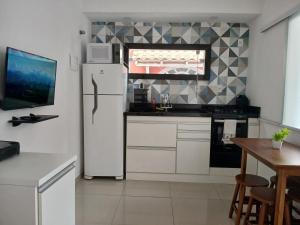 une cuisine avec un réfrigérateur blanc et une table dans l'établissement Hospedagem dos Massa- Casas no Centro de Arraial- Faça tudo a Pé!, à Arraial do Cabo