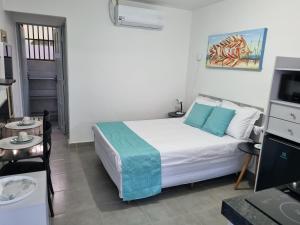 Un dormitorio con una cama, una mesa y un televisor. en RC FLATS apts 02 e 04, en Tamandaré