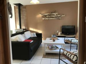 ein Wohnzimmer mit einer schwarzen Couch und einem Fernseher in der Unterkunft Maison 3* avec jardin, terrasse sud-ouest, proche mer et commerces, à Trégastel - FR-1-368-367 in Trégastel