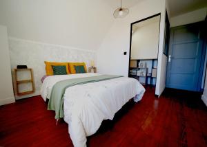 ein Schlafzimmer mit einem großen weißen Bett mit orangefarbenen und grünen Kissen in der Unterkunft Zénithouse in Éterville