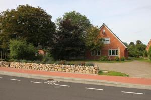a house with a stone retaining wall next to a road at Ferienhaus-Min-Drom in Sankt Peter-Ording