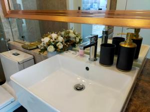 a bathroom sink with a mirror and flowers on it at The Empire Tower Jomtien KZi 2205 in Jomtien Beach +26 photos