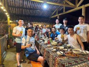 a group of people sitting around a table with food at Trường Giang Homestay in Cao Bằng