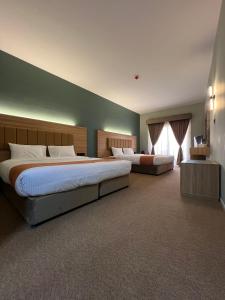ドバイにあるAygro Hotelの緑の壁のベッドルーム1室(ベッド2台付)