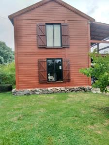 een houten huis met ramen en een tuin bij Cabaña El Banbi in La Coronilla