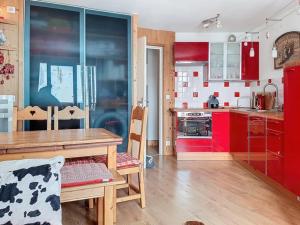 eine Küche mit roten Schränken und einem Holztisch in der Unterkunft Confort 2 pièces La Daille, accès direct pistes - FR-1-518-162 in Val dʼIsère