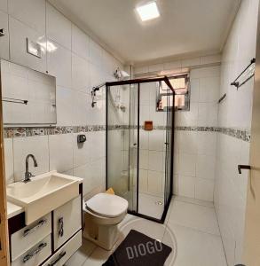 a bathroom with a shower and a toilet and a sink at apto frente praia pé na areia 2dorm wifi elevador Smart tv praia grande aviação - leia fotos in Praia Grande