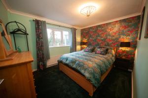 a bedroom with a bed with a floral wallpaper at Pheasant's Bank holiday cottage in Chapel en le Frith