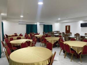 a room full of tables and chairs with green curtains at Hotel Plaza Corotú-HPC in Santiago
