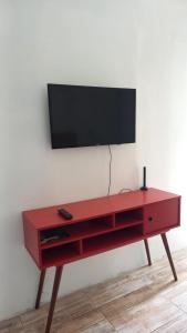 a red entertainment center with a flat screen tv on a wall at Apartamento aluguel temporada Torres-RS in Torres