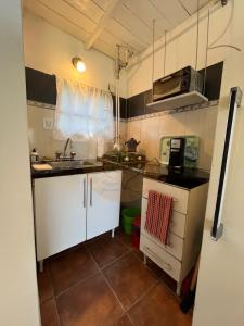 a small kitchen with white cabinets and a sink at Las Retamas in Chapadmalal +1 photo
