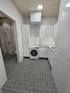 ロヴァニエミにあるLuxury Apartments Pannuのキッチン(白いキャビネット、洗濯機、乾燥機付)