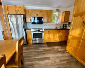 a kitchen with wooden cabinets and a stainless steel refrigerator at Chalet Sous Les Pins in Les Éboulements