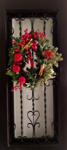 a christmas wreath on a metal gate with red flowers at LA CASA DEL VIENTO ATQ in Antequera