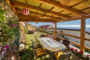 a patio with a table and chairs under a wooden pergola at Salvo's House in Furore