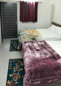 1 Schlafzimmer mit 2 Betten und 2 Teppichen auf dem Boden in der Unterkunft ERA HomeStay in Pachmarhi