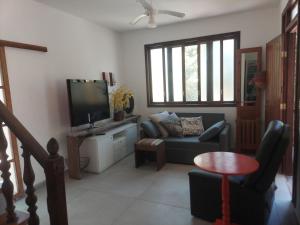a living room with a couch and a tv at Casa CANTIN DO ACONCHEGO na Praia de Taperapuan, Porto Seguro in Porto Seguro