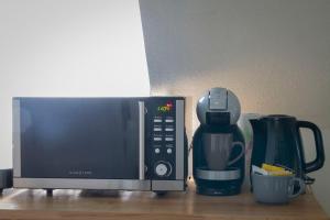 a microwave next to a coffee maker and a coffee pot at La Petite Parenthèse in Beure