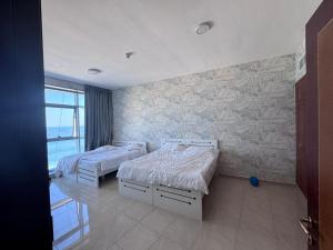 a bedroom with two beds and a stone wall at Sunrise Ajman sea view in Ajman  +15 photos