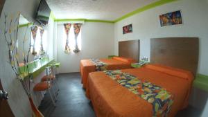 2 camas en una habitación con sábanas de color naranja en Hotel Yekkan, en Huauchinango