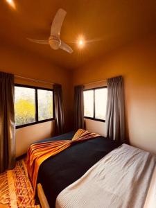 a bedroom with a bed and two windows at Villa SOLENSSE in Uvita