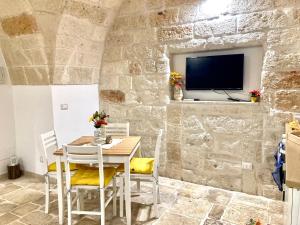 a dining room with a table and a tv on a stone wall at Antica Pietra in Polignano a Mare
