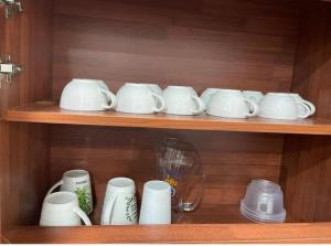 a shelf filled with white cups and saucers at RALI PD HOME D 16Pax karaoke and swimming pool in Port Dickson