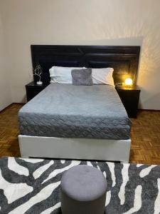 卢班戈Quartos privados em uma casa comum的一间卧室配有一张床、一个凳子和一张床架 更多1张照片