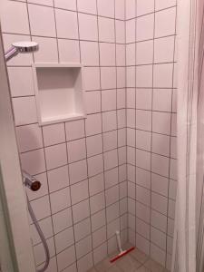 a white tiled bathroom with a shower with a red at Central cozy apartment in Amager in Copenhagen +15 photos