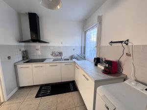 a small kitchen with white cabinets and a sink at Séjour détente et confort au calme d une impasse in Garges-lès-Gonesse