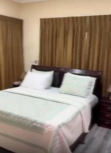 a bedroom with a large bed with white sheets and pillows at B4 Rentals in Accra