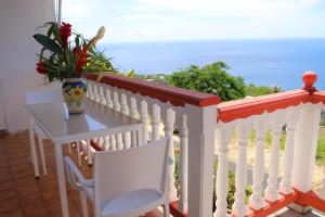 a white balcony with a table and a vase of flowers at Gîtes Dardanelle in Bouillante