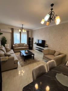 ein großes Wohnzimmer mit Sofas und Fernseher in der Unterkunft 2 bedroom apartment in rehab cityy in Burg el-Ḥudûd