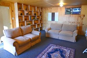 a living room with two couches and a rug at Barn Bed and Breakfast in Waitati